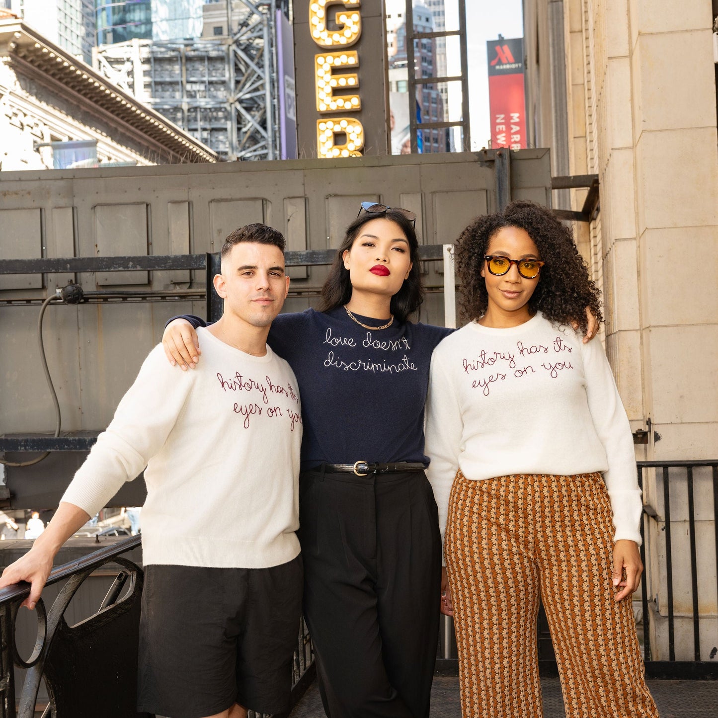 Three people standing together in an urban setting with a 'Rodgers' sign in the background.